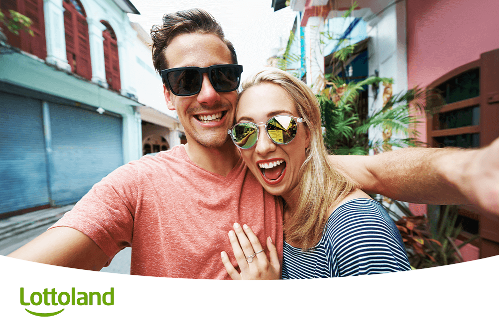 Lachendes Paar macht Selfie im Urlaub – mit den leiwanden Lotto-Tipps von Lottoland entspannt zum Spielglück